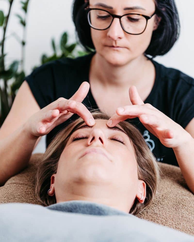 Therapeutische Hände führen eine Cranio-Sacral-Behandlung am Kopf eines Klienten durch.